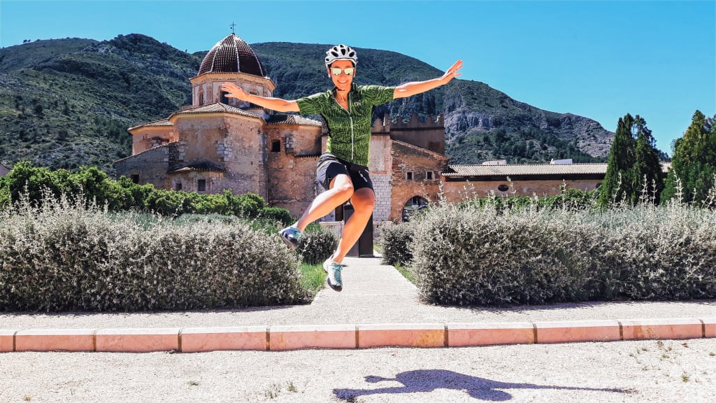 Ciclista felice davanti a una chiesa antica, vacanze in Spagna in bici